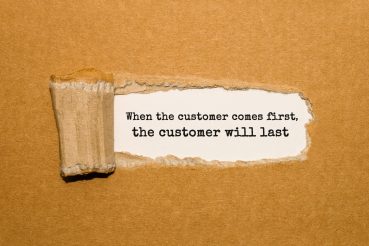The text When the customer comes first the customer will last appearing behind torn brown paper